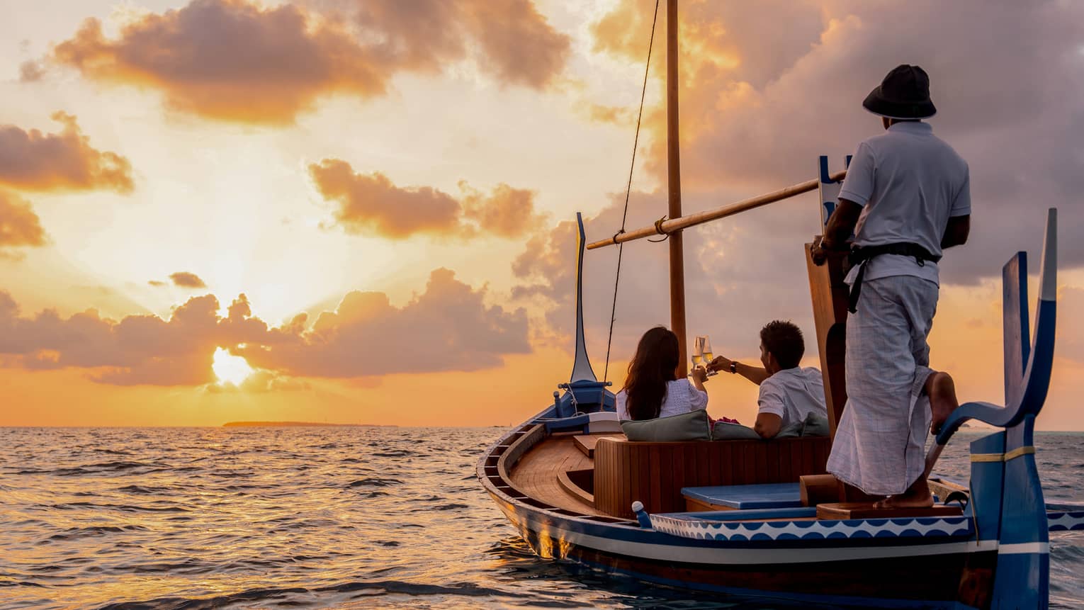 A traditional dhoni on the water at sunset